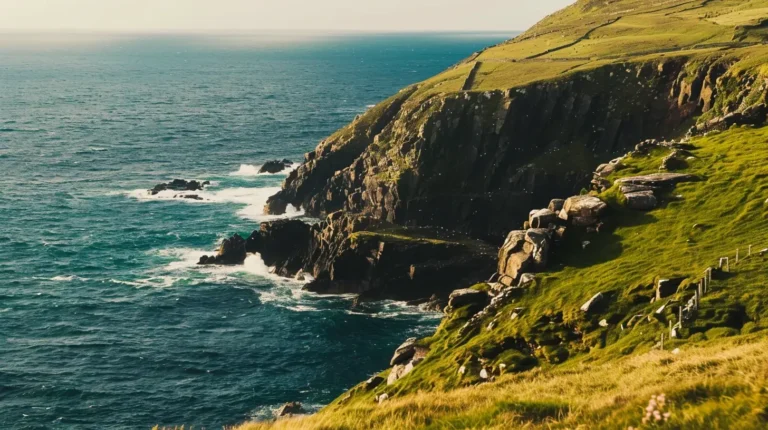 Coastal cliffs covered with greenery meet the blue ocean waves crashing against the rocks below. The scene captures the rugged, natural beauty of the landscape under a clear sky, with rolling hills and the white foam of the surf adding dynamic contrast—an idyllic spot suggested by your AI travel planner. - easytrip.ai